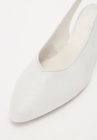 Chaussure slingback en suède blanc avec un bout pointu et des côtés dégagés. Texture lisse avec un éclat subtil. Design minimaliste.