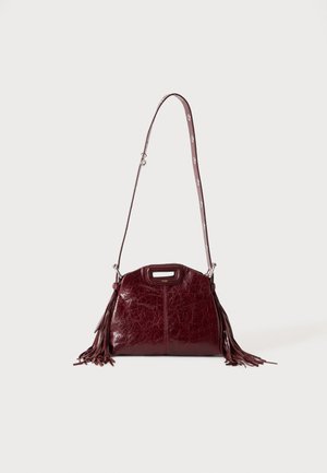 Sac à bandoulière en cuir rouge foncé avec des détails à franges et une bandoulière réglable avec boucle argentée sur un fond clair uni.