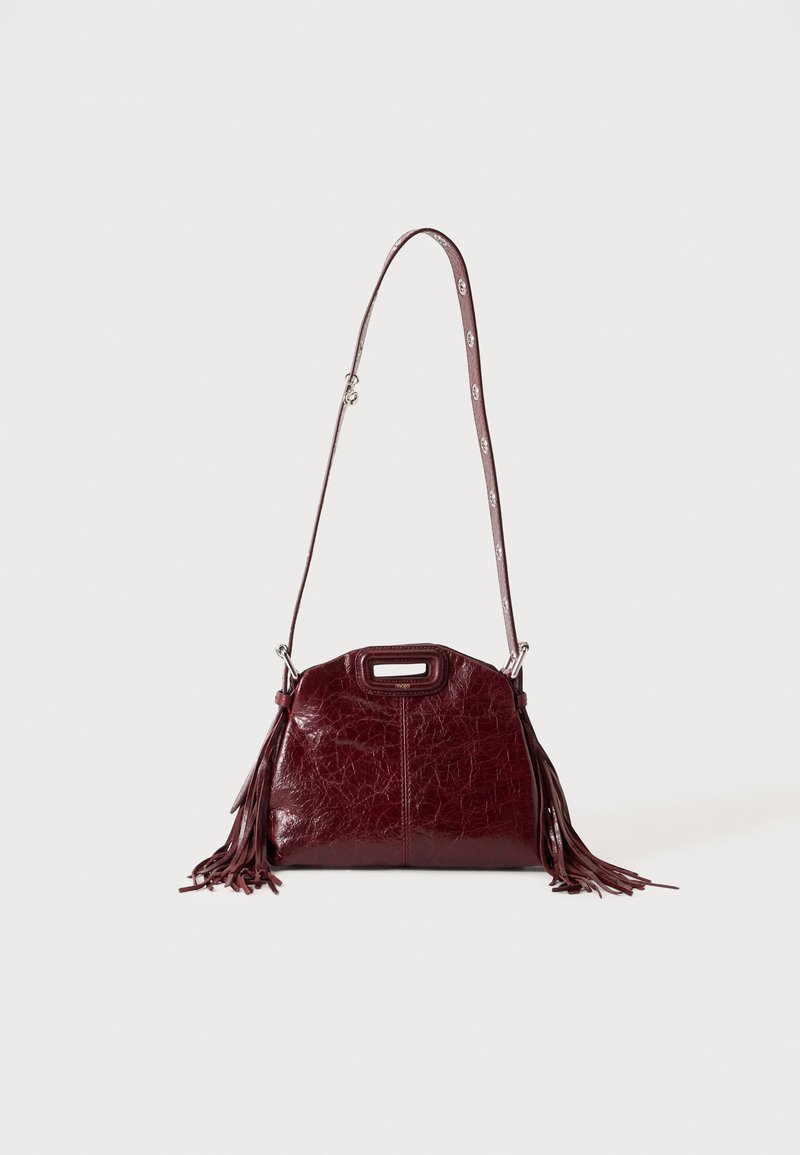 Sac à bandoulière en cuir rouge foncé avec des détails à franges et une bandoulière réglable avec boucle argentée sur un fond clair uni.