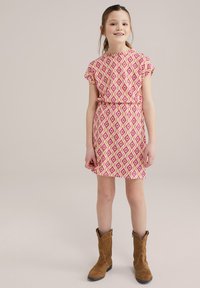 Kurzärmliges Kleid mit einem rosa-weißen Diamantmuster, tailliert, kombiniert mit braunen Cowboy-Stiefeln. Glatte Stoffstruktur.