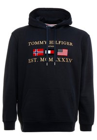 Black hoodie with front kangaroo pocket, gold lettering, and three flags (Norway, Denmark, USA) below "TOMMY HILFIGER EST. MCMXXXV."
