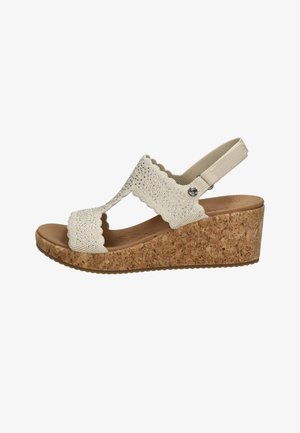 Beige sleehak sandaal met kurken zool, gegolfde gebreide bandjes versierd met kleine glanzende kralen en een elastisch hielbandje.