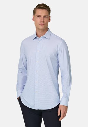 Camicia azzurro chiaro a maniche lunghe con colletto con bottoni, caratterizzata da un motivo a quadretti sottile e orlo arrotondato. Realizzata in tessuto liscio.