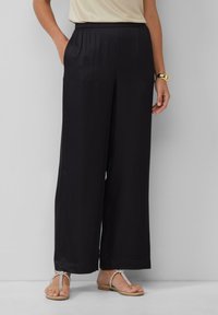 Zwarte wijde broek van lichtgewicht stof met een elastische tailleband en zijzakken, met een gladde textuur en een vloeiend ontwerp.