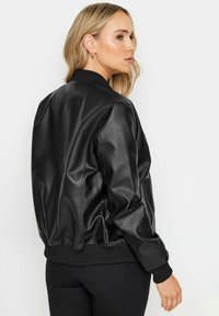 Svart konstläder bomberjacka med ribbad krage och muddar, med en avslappnad passform och slät textur. Visad från en sidovinkel.