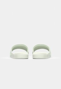 Ljusgröna sandaler med öppen hälskaft och rundade toppband. Texturerad fotbädd med platt sula; minimalistisk design och varumärkning.