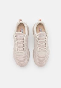 Ljusrosa träningsskor med en texturerad stickad ovandel, snörning fram och gummisulor. Har logotyp på tungan och häl.