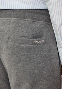 Szürke pulóver anyaga hátoldali zsebbel, amelyen a "HACKETT" logó hímzett részletekkel látható. Az derékpánt rugalmas, a kényelem érdekében.