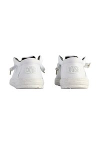 Zapatos casuales blancos con una parte superior de tela texturizada, forma redondeada y suela de goma con un diseño moteado. Logo "HEY DUDE" estampado en el talón.