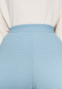 Helleblaue, strukturierte Hose mit karierter Musterung, ausgestattet mit einem elastischen Bund für zusätzlichen Komfort.