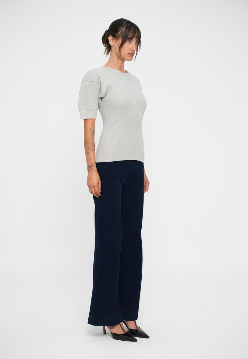 Gray short-sleeve top with a rounded neckline paired with navy wide-leg trousers and black pointed-toe heels on a plain background.
