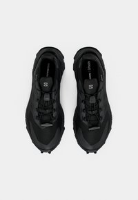 Pár čiernych trailových bežeckých topánok Salomon s rýchlym šnurovacím systémom, pohľad zhora na bielom pozadí.