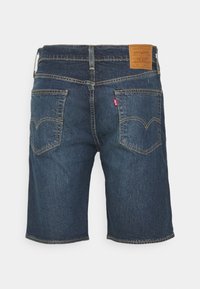 Shorts en denim bleu foncé avec deux poches arrière, des surpiqûres contrastantes, un patch de marque Levi's marron et une étiquette rouge avec le logo Levi's sur une poche.