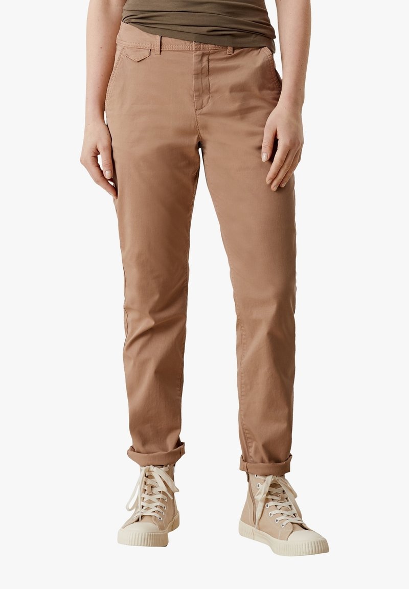 Ljusbruna byxor med slim fit, gjorda av mjukt bomullsmaterial. Har raka ben och uppvikta fållar, parat med beige högstövlar.