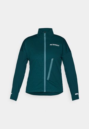 Teal treningsjakke med høy krage, full glidelås foran, sidelommer med glidelås og geometrisk mønster på øvre del. Har reflekterende detaljer.