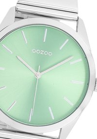 Montre Oozoo ronde avec un cadran vert menthe à texture brossée, des index horaires argentés et un bracelet en argent poli.