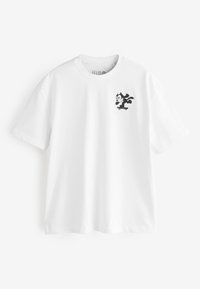 T-shirt en coton blanc avec un chat noir dessiné en cartoon sur un skateboard. Manches courtes et col rond. Texture lisse, coupe décontractée.