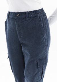 Donkerblauwe corduroy broek met een elastische tailleband, zijzakken en details van cargozakken, met een zachte textuur en een relaxte pasvorm.