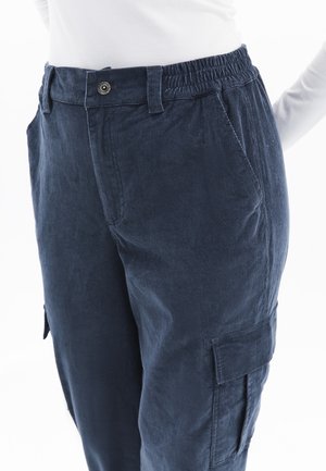 Dunkelblaue Cord-Hosen mit elastischem Bund, Seitentaschen und Cargo-Taschen-Details, die über eine weiche Textur und eine lockere Passform verfügen.