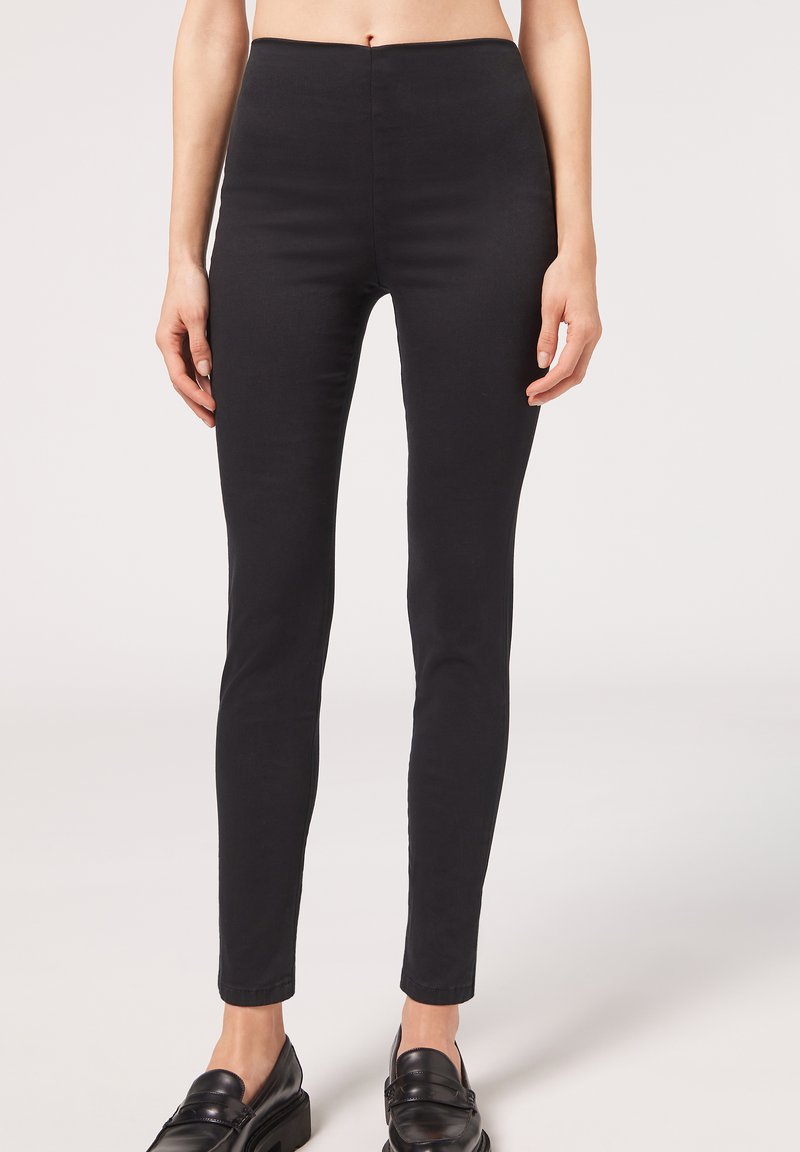 Svarta leggings i stretchmaterial, med hög midja och figurnära passform, som sträcker sig ner till ankellängd.