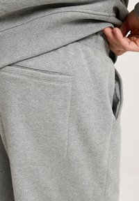 Szare dresowe spodnie o miękkiej teksturze, elastycznej talii, bocznych kieszeniach oraz prostym wzorze. Skoncentrowane na komforcie i praktyczności.