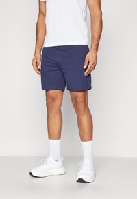 Bermudas de algodón azul marino con un corte relajado, que cuentan con una cinturilla elástica. Combinadas con una camiseta blanca y zapatillas deportivas blancas.