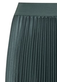 Gonna plissettata in tessuto verde scuro, con una vita liscia e pieghe verticali che creano texture e dimensione.