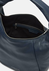 Granatowa skórzana torba na ramię o gładkiej fakturze, z zamkiem błyskawicznym i kieszenią wewnętrzną. Posiada srebrne akcesoria i detal z logo.