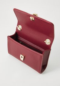 Burgundy leather handbag with gold hardware, textured exterior, open flap, and interior zip pocket for organization.