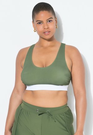 Olive green sports bra with a white band at the bottom, made of smooth, stretchy fabric. Features wide straps and a scoop neckline.