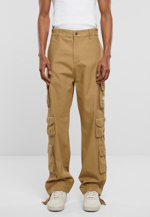 Brune cargo bukser lavet af bomuld, med flere sidelommer, lige ben design og en frontknap lukning. Bæres med hvide sneakers.