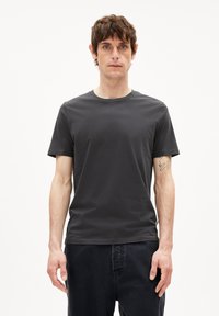 Dunkelgraues T-Shirt mit kurzen Ärmeln aus Baumwolle. Es hat einen runden Halsausschnitt und einen lässigen Schnitt, kombiniert mit dunklen Jeans.