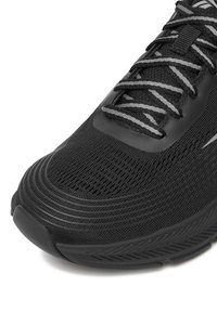 Schwarzer Sportschuh mit strukturiertem Stoffobermaterial, schlankem Design, markantem Schnürsystem und Gummisohle mit gemustertem Profil.