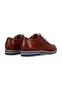 Chaussures en cuir marron avec une finition lisse, dotées d'une semelle rayée blanche et marine en contraste. Bout arrondi et design minimaliste.