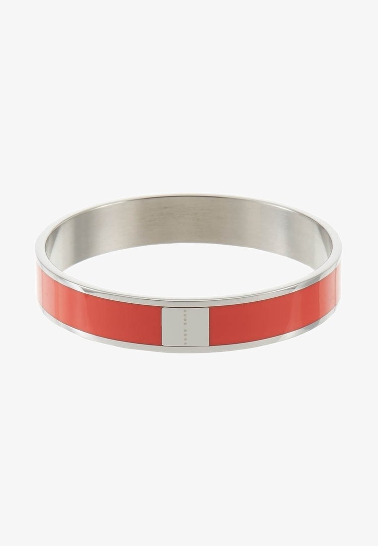 Bracelet jonc en métal argenté avec une incrustation lisse en émail rouge et une petite plaque rectangulaire en argent au centre.