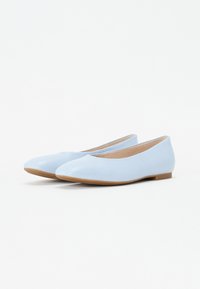Ballerines en cuir verni bleu clair avec un bout rond et une semelle plate, présentant une texture lisse et un design minimaliste.