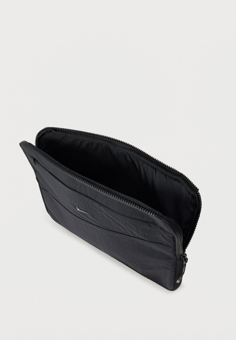 Neceser negro con cremallera con compartimento principal abierto y pequeño bolsillo frontal, hecho de tela texturizada sobre un fondo blanco liso.