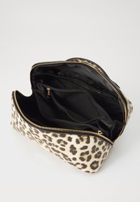 Tasche mit Leopardenmuster und schwarzem Innenraum, ausgestattet mit einem Reißverschluss und mehreren Fächern zur Organisation. Akzente in goldfarbener Hardware.