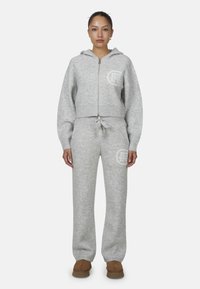 Szary dzianinowy hoodie z zamkiem błyskawicznym i logo, w komplecie z pasującymi dresami. Posiada ściągacze przy mankietach i dolnym brzegu, miękką fakturę oraz luźny krój.