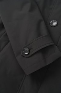 Schwarze isolierte Jacke mit glatter Textur, geknöpften Manschetten und einem taillierten Design mit diagonalem Steppmuster.