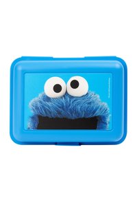 Una lunch box blu di plastica presenta un design di un personaggio peloso blu, con grandi occhi bianchi e una bocca nera su uno sfondo blu.