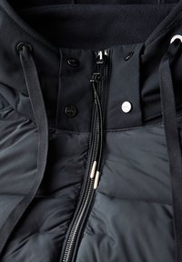 Schwarze Daunenjacke mit detailliertem Design, vorderem Reißverschluss, Kordelzugkapuze, Druckknöpfen und einer weichen Fleece-Innenausstattung.