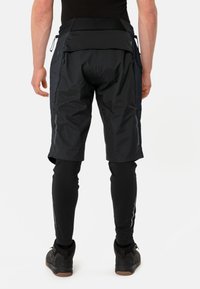 Zwarte shorts met een aansluitend ontwerp, gemaakt van lichtgewicht materiaal, voorzien van ritsen en een mesh-panel. Draag ze over zwarte leggings en schoenen.