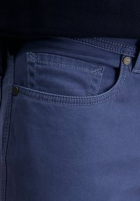 Blaue Jeans aus Baumwoll-Denim mit einer standardmäßigen Vorderstasche, verstärkten Nähten und einem Metallknopfakzent am Bund.
