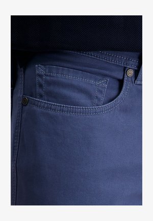 Blauwe katoenen denim jeans met een standaard voorzak, versterkte stiksels en een metalen knoopaccent op de tailleband.