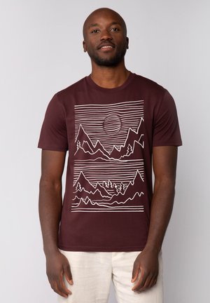 T-shirt en coton bordeaux avec un design graphique de montagne et de soleil blanc, des lignes horizontales, un col rond et des manches courtes.
