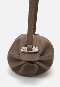 Brown leather handbag with a rounded shape, gathered texture, and a silver clasp accent. Features a single strap for carrying.