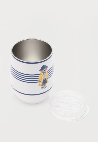 Λευκό ταξιδιωτικό κύπελλο με μπλε ρίγες, με ένα αρκουδάκι σε κίτρινο αδιάβροχο και μπλε καπέλο, με ένα διαφανές πλαστικό καπάκι δίπλα του.