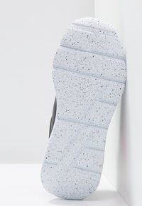 La semelle de la chaussure présente un caoutchouc blanc texturé avec des éclats noirs, une forme incurvée et un motif de sculpture distinct pour une meilleure adhérence.