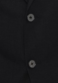 Schwarze Leinenjacke mit zwei grauen Knöpfen und einer strukturierten Oberfläche. Das Design umfasst einen einreihigen Verschluss mit einem dezenten Gewebemuster.